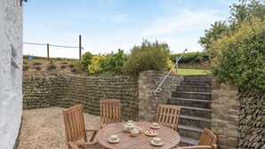 A stone wall, a wooden table with chairs, and a staircase. - 3 Bed in Barnstaple (oc-wayco) (Shirwell)