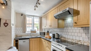 A kitchen with wooden cabinets, a dishwasher, a stove, and a microwave. - 3 Bed in Barnstaple (oc-wayco) (Shirwell)