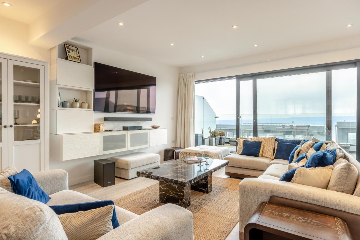 A modern living room with a flat-screen TV, comfortable seating, and a large window offering a view.