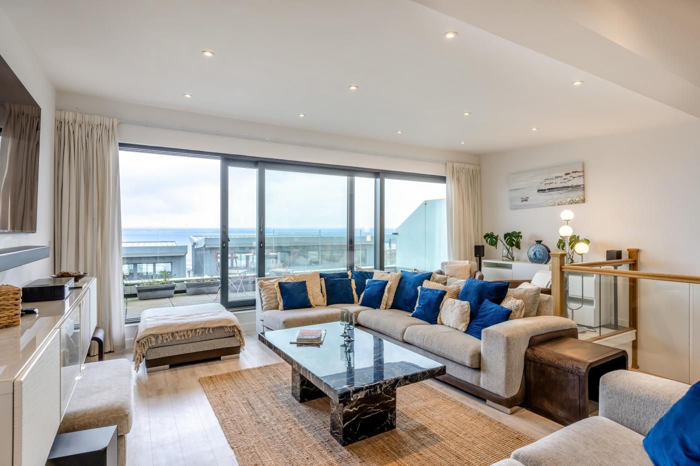 A modern living room with a large sofa, a coffee table, and a view of the cityscape.