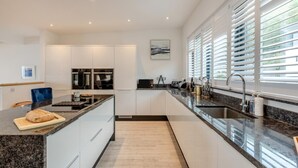 Una cocina moderna con armarios blancos, encimera de granito y horno empotrado.