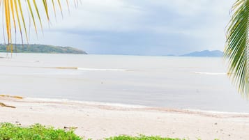 A beach with calm waters, a sandy shore, and distant landforms.