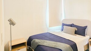 Ein Schlafzimmer mit einem Bett, einer Nachttischlampe, einem Fenster und einer Klimaanlage.