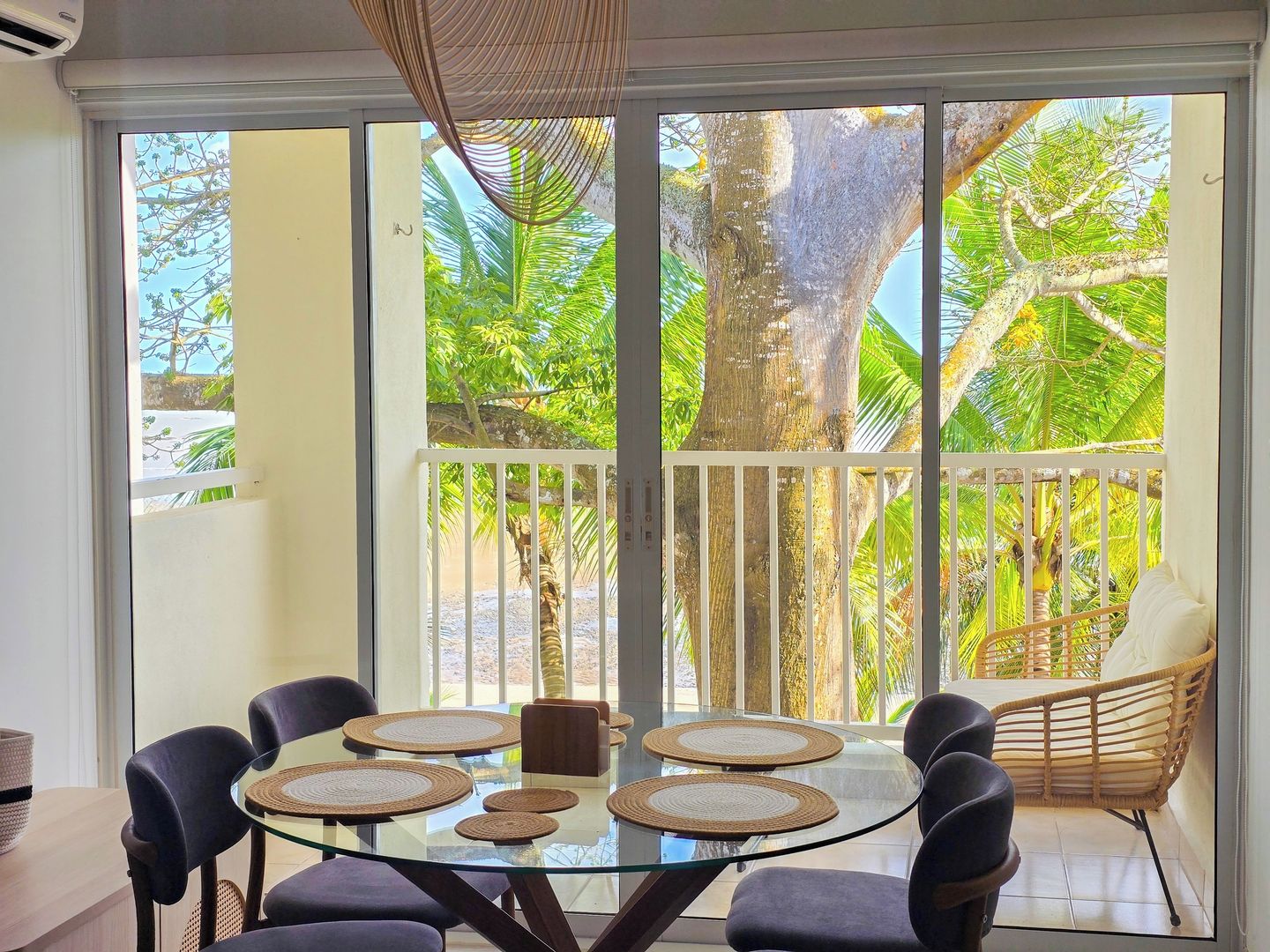 A dining area with a glass table, woven placemats, and chairs.