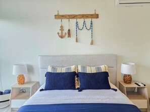 A bedroom with a bed, two nightstands, a wooden wall hanging, and a lamp on each nightstand. - The Nautique - Loft front beach (Arraiján)