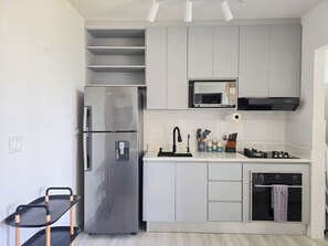 Une cuisine moderne équipée d’un réfrigérateur en acier inoxydable, d’un four à micro-ondes, d’une cuisinière à gaz et d’un four encastré.