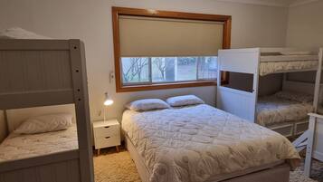 A bunk bed room with a window, a bedside lamp, and a carpeted floor.