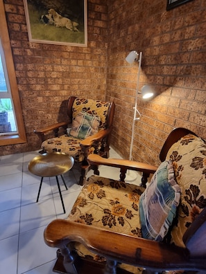 A room with a brick wall, a painting, a sofa set, a table, and a floor lamp.