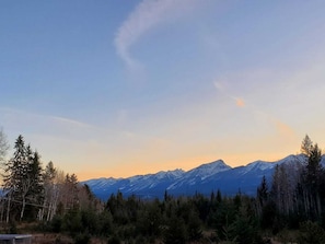 Un paysage de montagne avec des sommets enneigés et une forêt au premier plan.