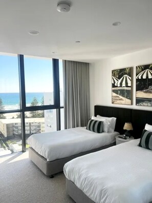 A hotel room with two beds, a large window with a view of the sea, and a ceiling with recessed lighting. - Esprit Holidays Rainbow Bay (Coolangatta)