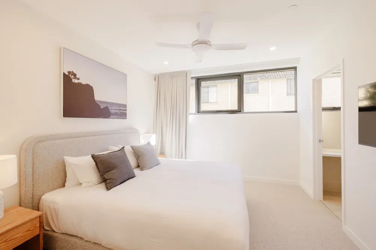 Ein Schlafzimmer mit einem Bett, einem Deckenventilator, einem Fenster und einem Bild an der Wand.