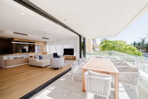 A modern living space with a dining area, a kitchen, and a balcony with a view. - Esprit Holidays Rainbow Bay (Coolangatta)