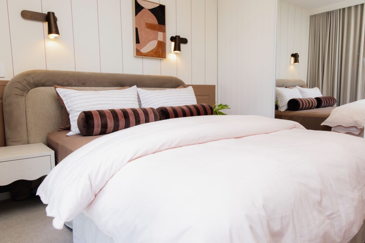 Ein modernes Schlafzimmer mit einem großen Bett, Nachttischen und Wandleuchten.