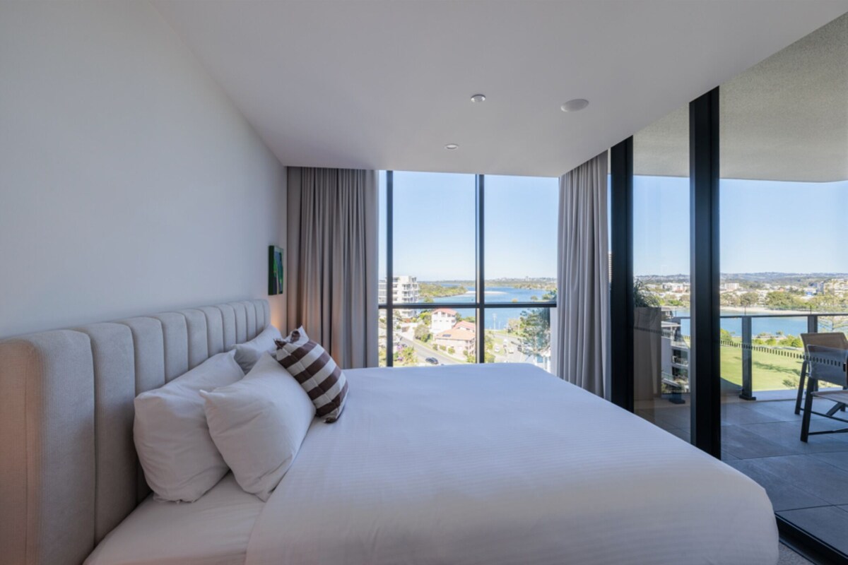 Ein Hotelzimmer mit einem großen Bett, Blick auf die Stadt und einem Balkon.