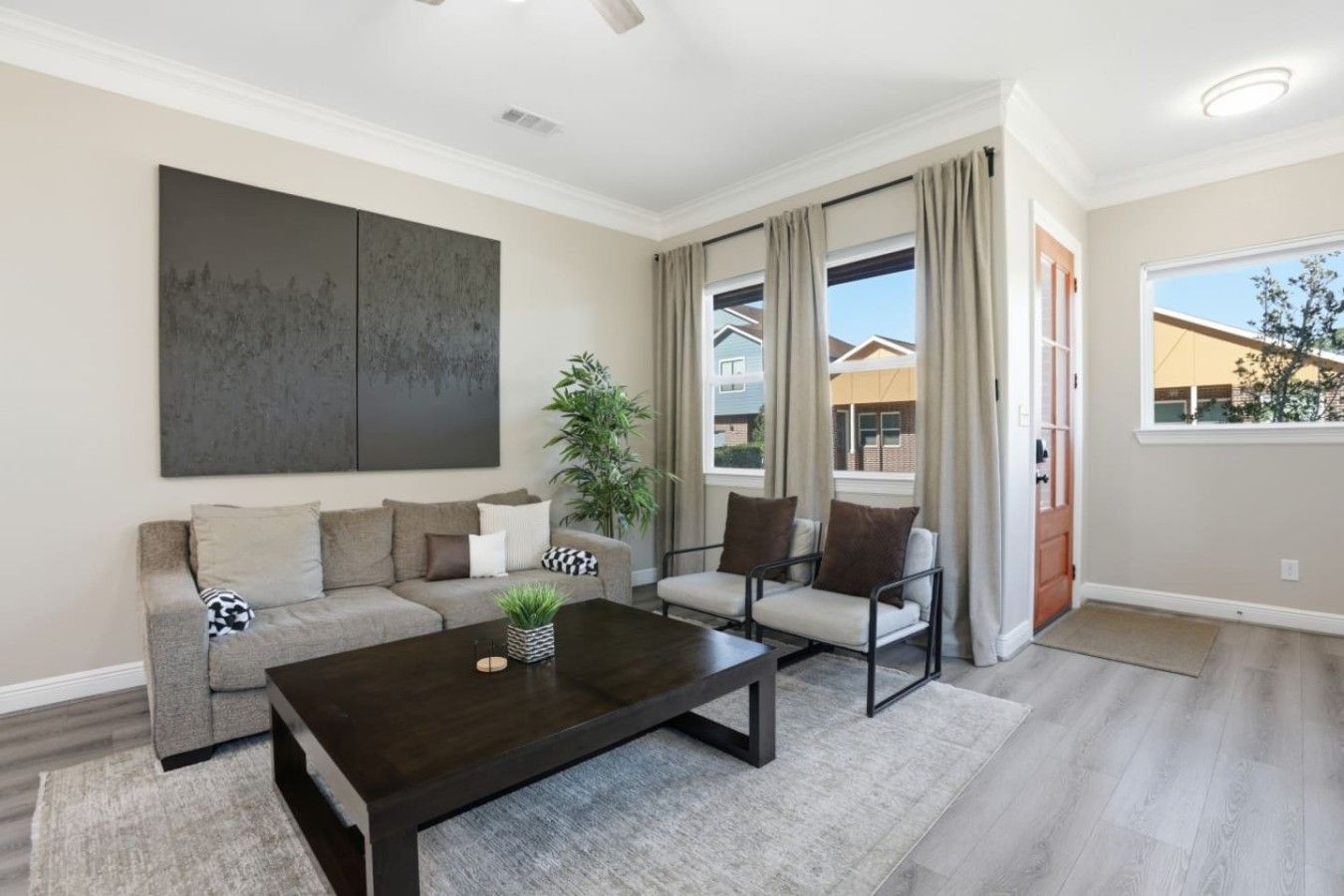 A modern living room with a dark wood coffee table, a grey sofa, and two armchairs.
