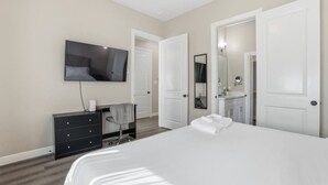 Habitación de hotel con una cama grande, un televisor montado en la pared, un escritorio con una silla y un armario.