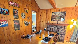 Een houten eetkamer met een lange tafel gedekt voor vier personen, omringd door houten stoelen met groene kussens.