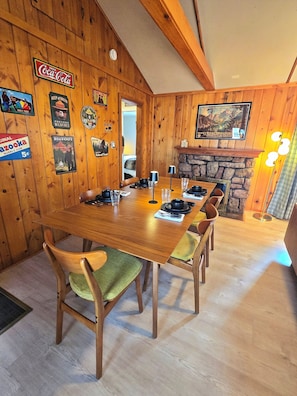 A wooden dining room with a long table set for four, surrounded by wooden chairs with green cushions. - "Camp Cabin"  2-bedroom cabin in serene Estes Park (Estes Park)