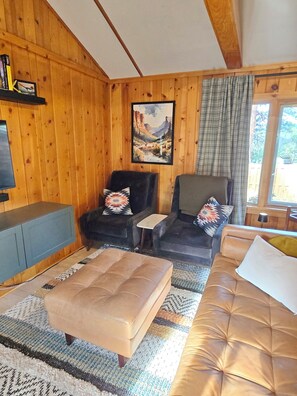 A wooden interior with a sofa, two armchairs, a small table, and a television. - "Camp Cabin"  2-bedroom cabin in serene Estes Park (Estes Park)