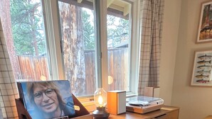 Een houten dressoir met lades, een lamp en een ingelijst schilderij erboven.