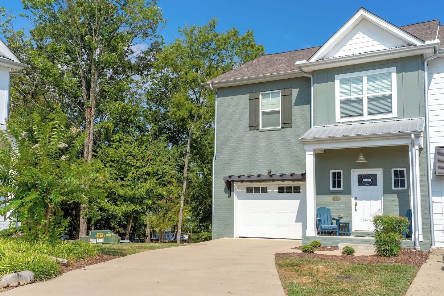 A two-story residential building with a garage, a front porch, and a small front yard.