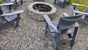 Una casa con una chimenea rodeada de sillas Adirondack.