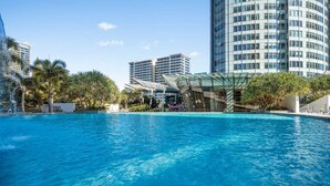 A swimming pool with modern buildings in the background. - Elevé at Q1 - Spectacular Beach + Hinterland views (Surfers Paradise)