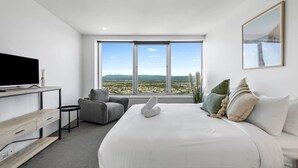 A modern hotel room with a large bed, a desk, a chair, and a television. - Elevé at Q1 - Spectacular Beach + Hinterland views (Surfers Paradise)