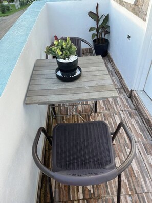 Un balcon avec une table en bois, un pot de fleurs, une chaise et une petite piscine.
