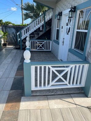 Un bâtiment à deux étages, doté d’un escalier, d’une porte blanche et d’un balcon avec une balustrade.