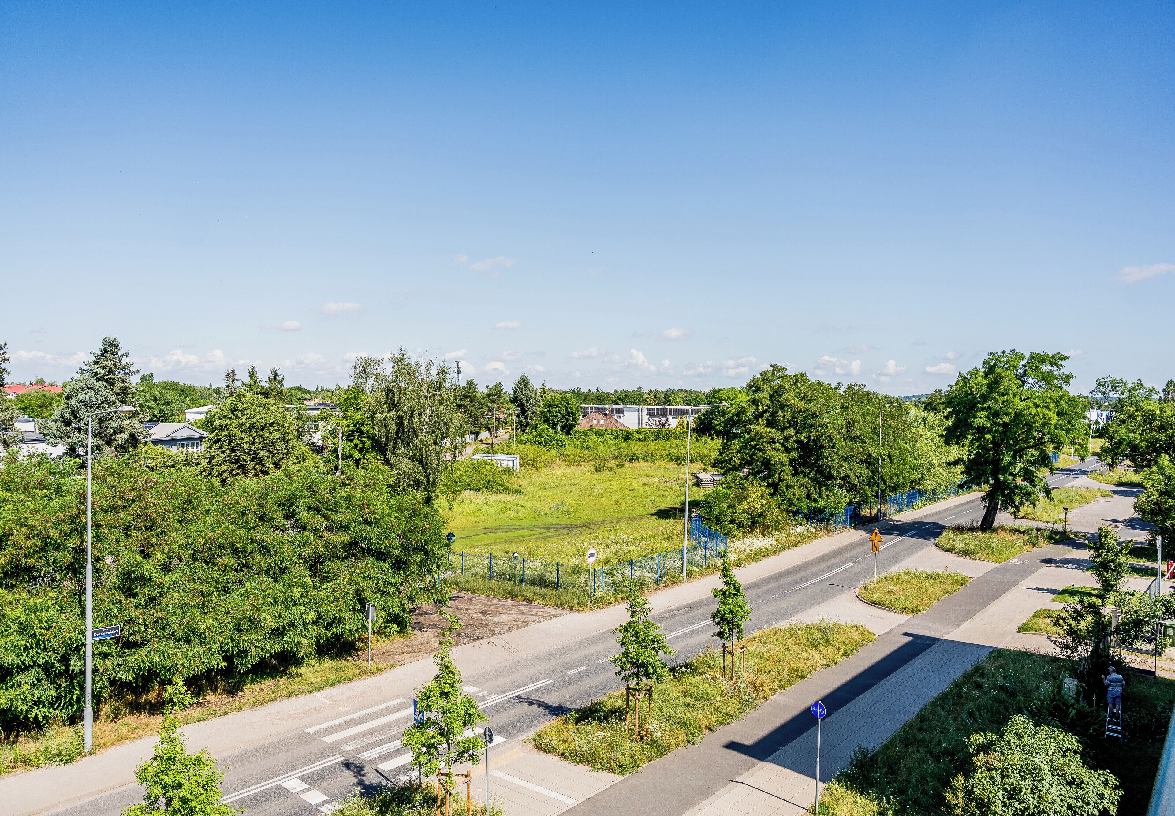 Zona residencial con carretera, aceras y áreas verdes.