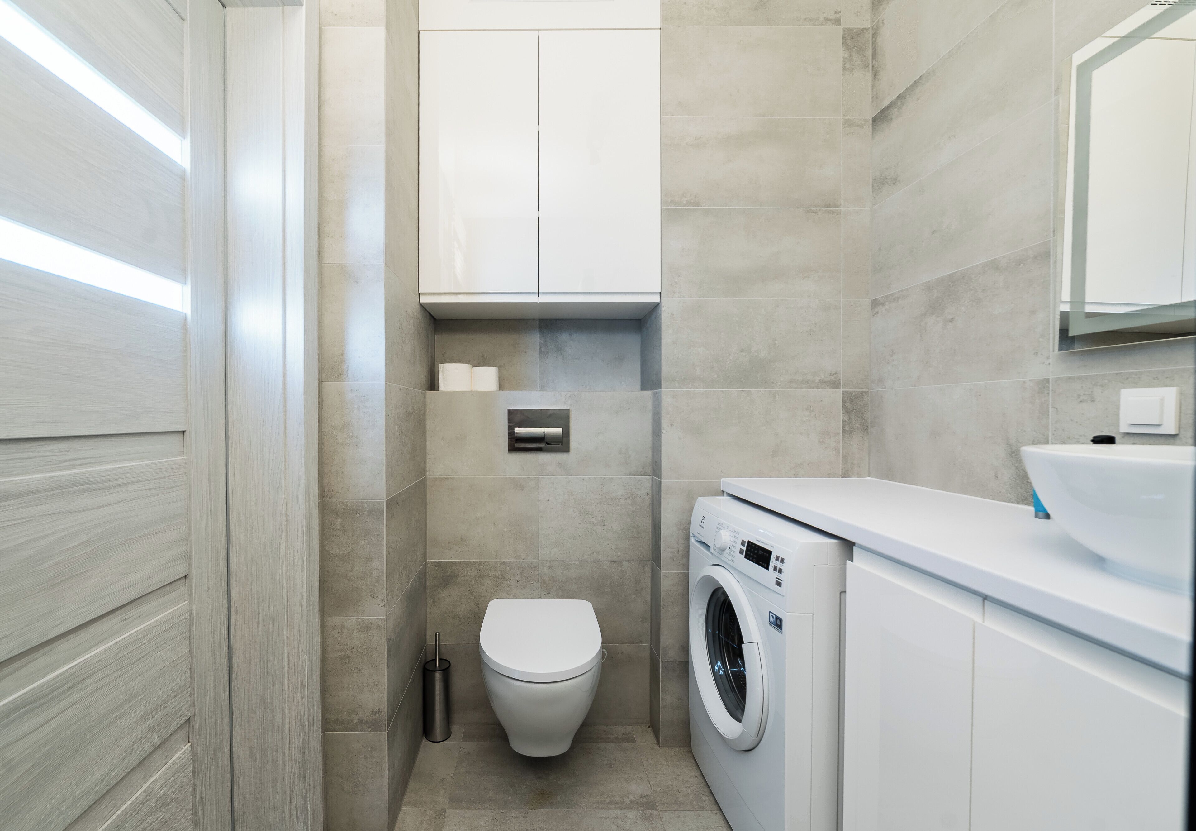 Un bagno moderno con un water, una lavatrice e un lavandino.