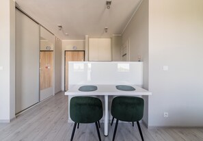 Eine moderne Küche mit weißer Arbeitsplatte, zwei grünen Stühlen und einer Holztür im Hintergrund.