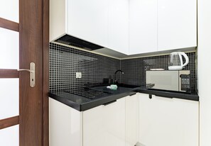 A kitchen with a microwave, kettle, and black countertop. - Opata Hackiego Urban Stay Apartment (Gdynia)