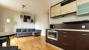Eine moderne Küche mit dunklen Schränken, einem eingebauten Backofen und einem Flachbildfernseher.