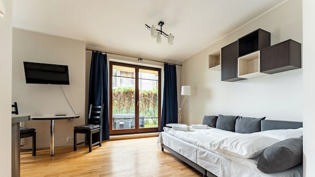 Ein modernes Hotelzimmer mit Bett, Schreibtisch, Stuhl und einem an der Wand befestigten Fernseher.