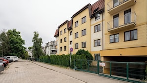 Ein mehrgeschossiges Wohngebäude mit Balkonen, einem umzäunten Parkplatz und einem Verbotsschild.