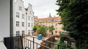 Un balcone con vista su un cortile, un'auto rossa e un edificio con una torre.