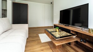 En moderne stue med en sofa, et sofabord, et fjernsyn og et tv-møbel i træ.