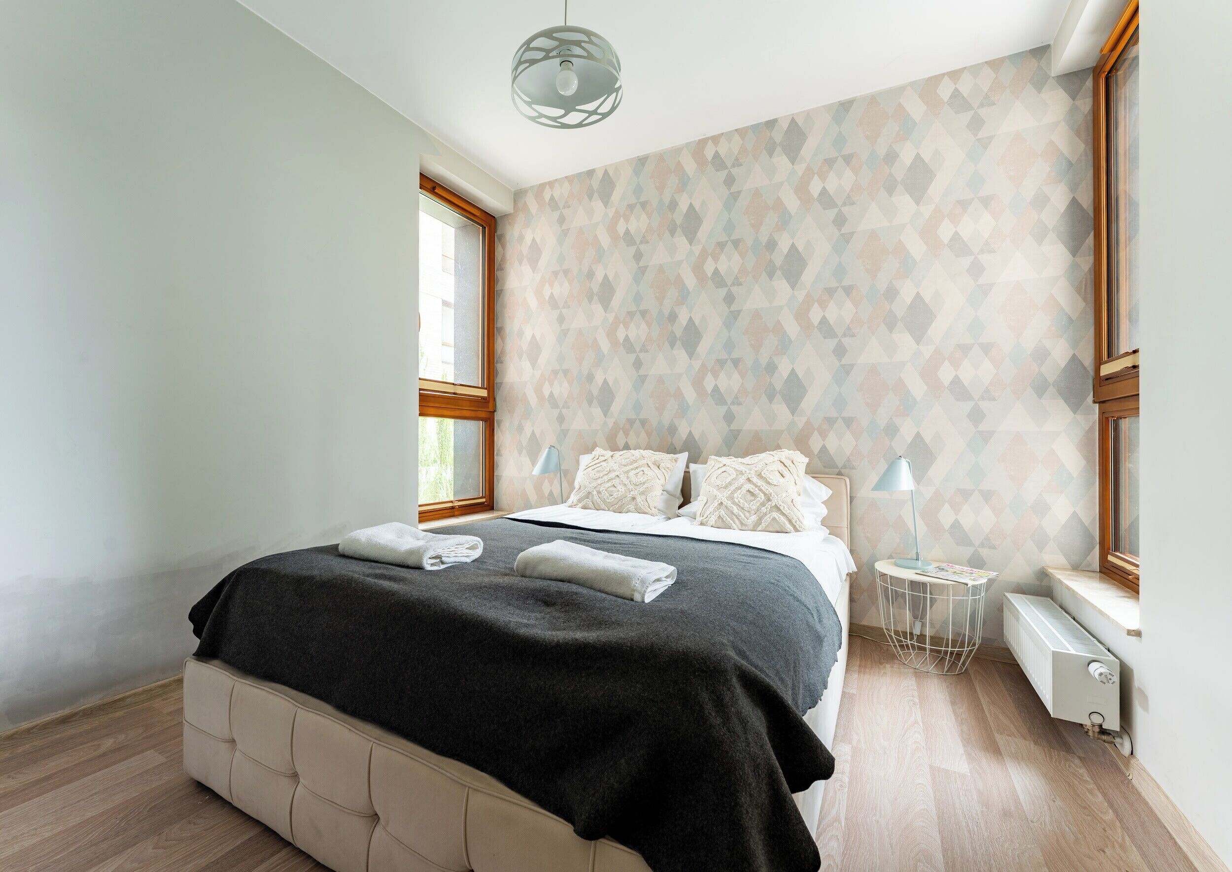 Un dormitorio con cama, mesita de noche, lámpara y radiador.