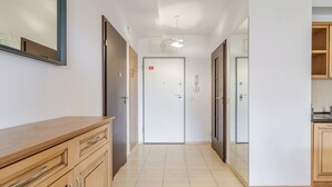 Ein Korridor mit Holzausbau, Fliesenboden und einer Tür mit Lichtschalter.