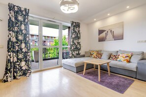 Un salon moderne avec un canapé gris, une table basse en bois et des rideaux à motifs floraux.