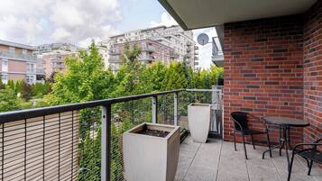 A balcony with a metal railing, two potted plants, and a table with two chairs.