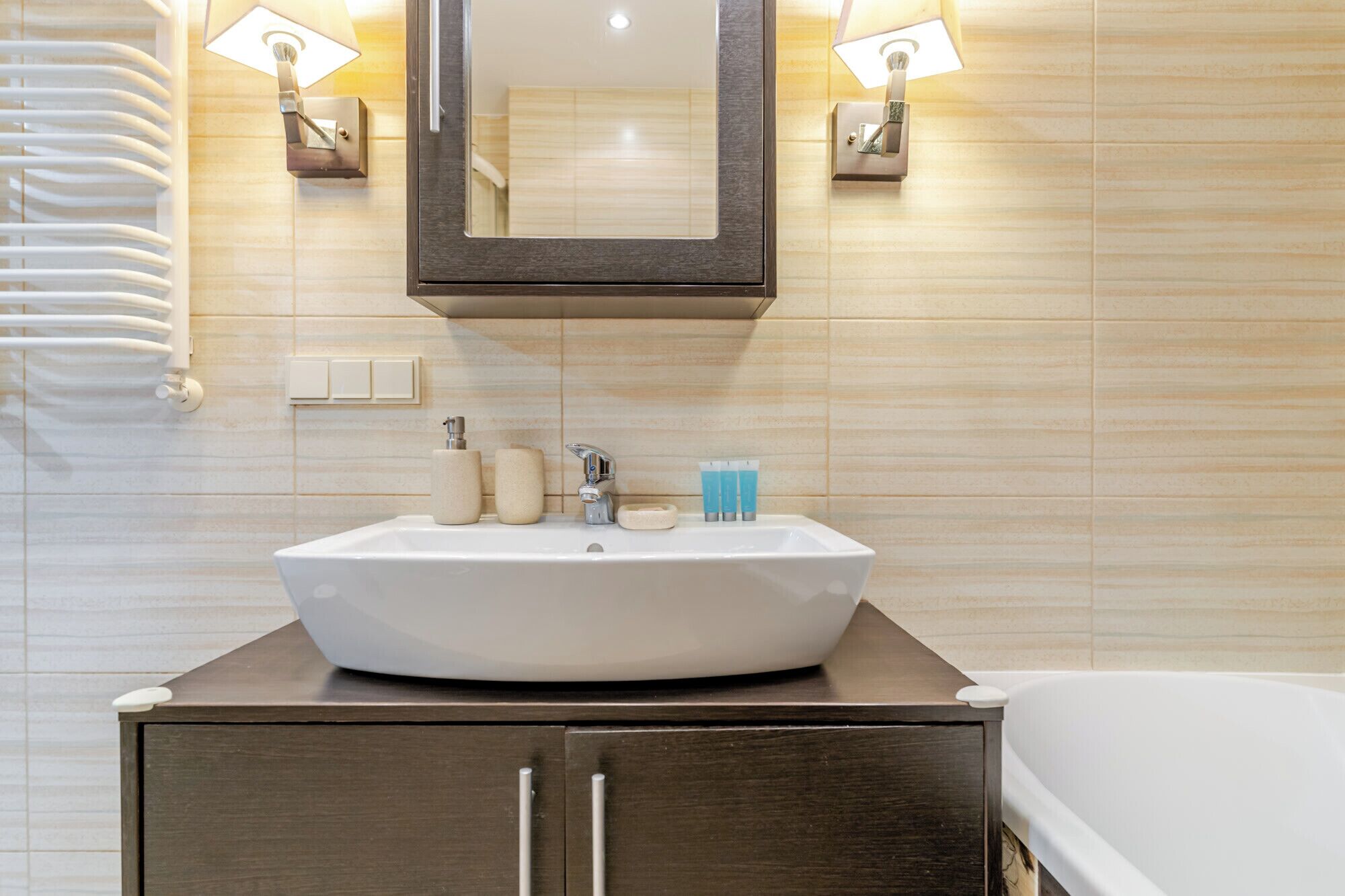 A bathroom with a white sink, a mirror, and two wall-mounted lights.
