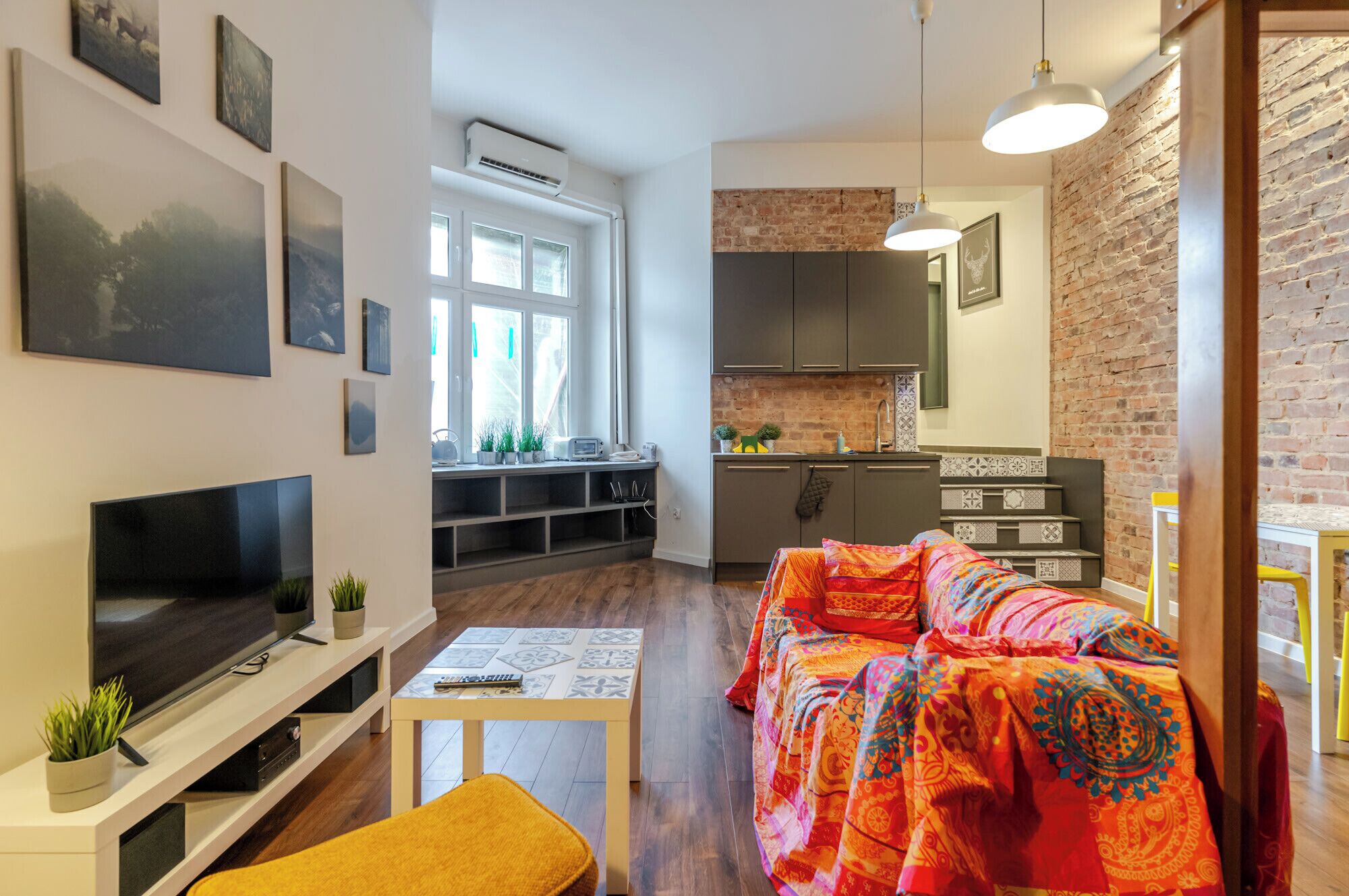 Un salon moderne avec un téléviseur, un canapé et une petite table.