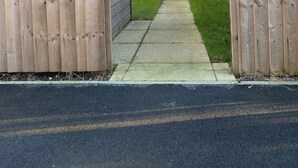 Una propiedad residencial con una casa de ladrillo, una cerca de madera y un camino de entrada pavimentado.