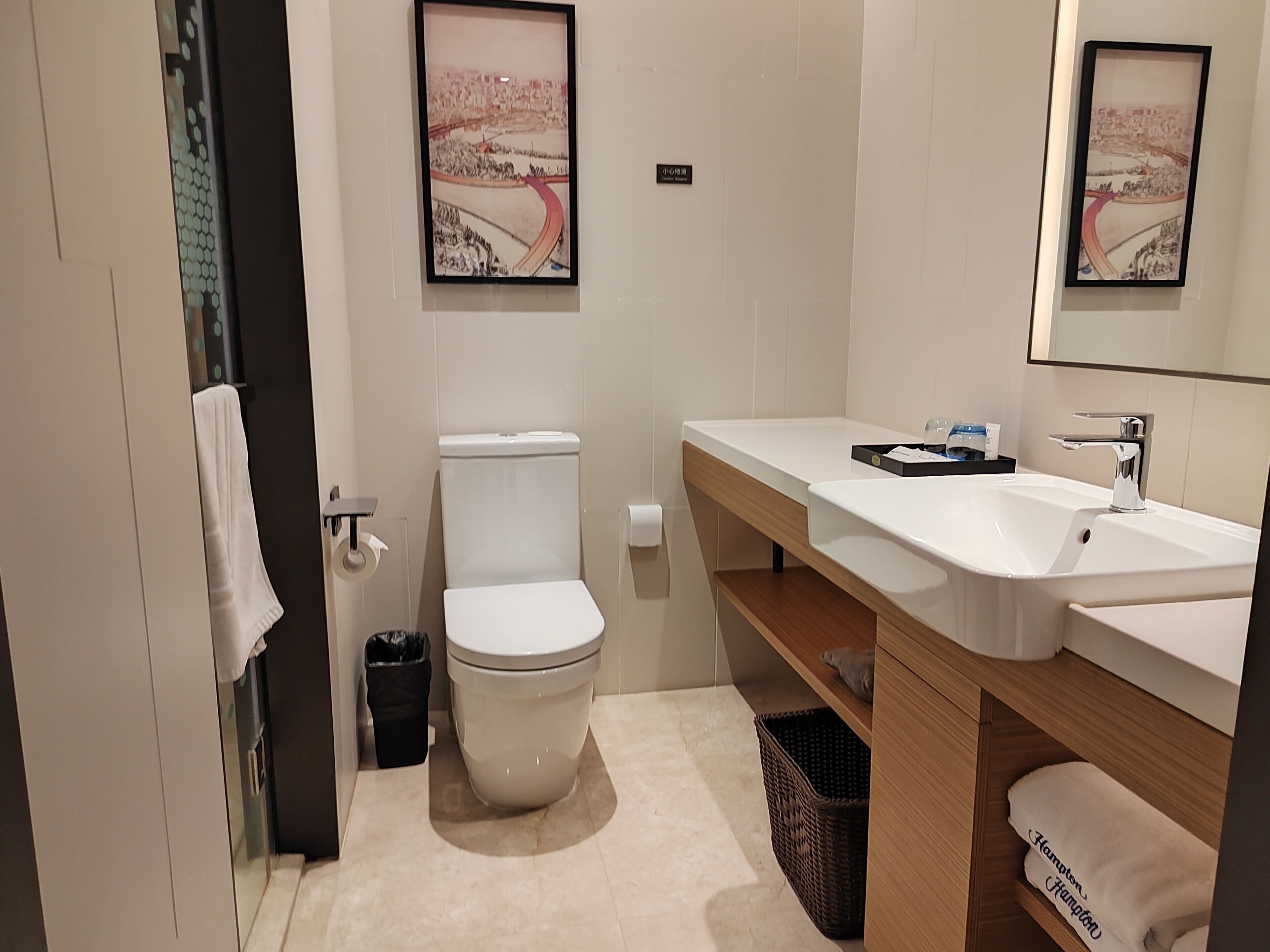 Un baño moderno con inodoro, lavamanos y un cuadro en la pared.