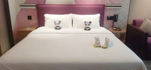 Een hotelkamer met een bed, twee kussens met pandabeeldjes, een nachtkastje met een telefoon, en een stoel.