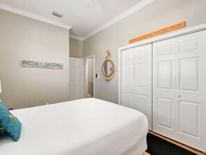 Ein Schlafzimmer mit Bett, Kleiderschrank, Spiegel und motivierenden Wandbildern.