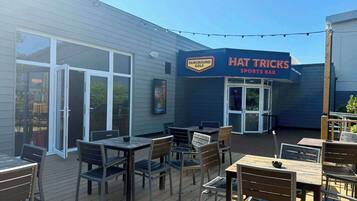 An outdoor seating area with tables and chairs, a sports bar sign, and a golf sign.